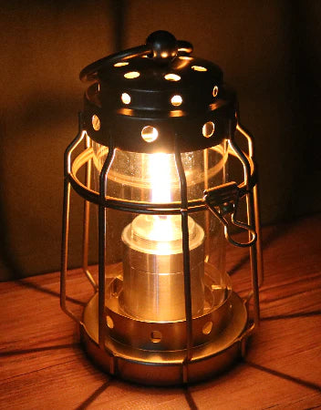 F Plus Duralumin Oil Candle — lit, in a vintage-style lantern with a warm glow on a wooden surface