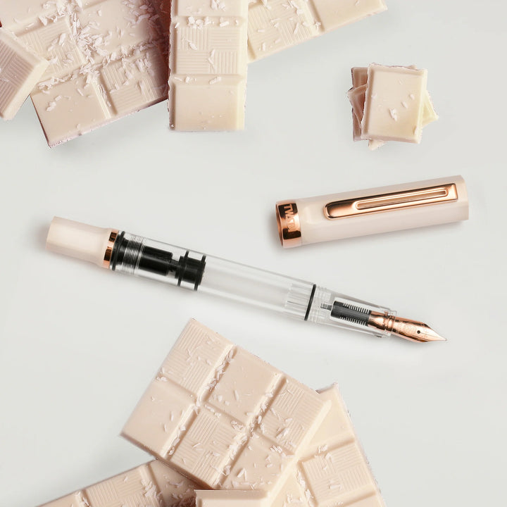 TWSBI ECO Fountain Pen – Creme Rose Gold with rose gold accents on a light surface with decorative chocolates.