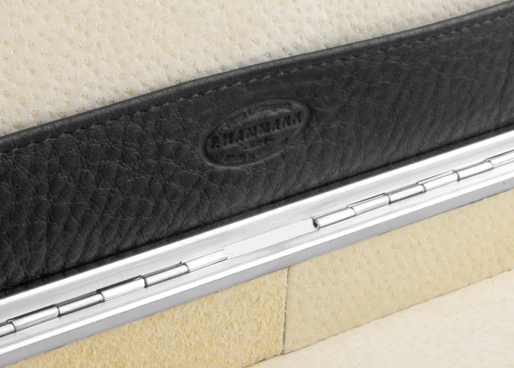 Macro shot of the F. Hammann 1864 heritage logo embossed on black leather above the silver piano hinge and suede lining.