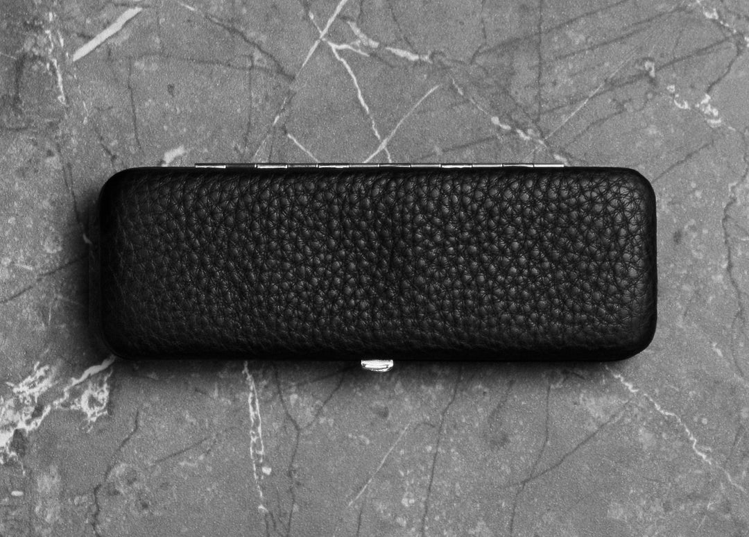 Top-down view of the sleek F. Hammann 3983 black leather 3-pen case resting flat on a grey marble surface.