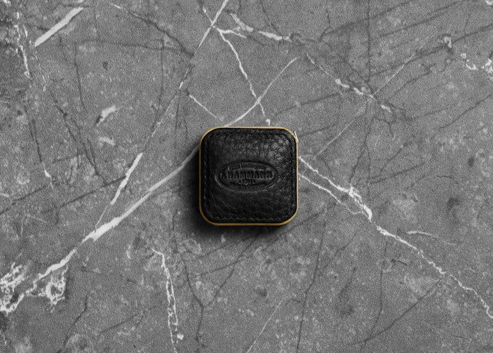 Top-down photograph of the F. Hammann 5205 Black Chervo Leather Tape Measure resting on grey marble.