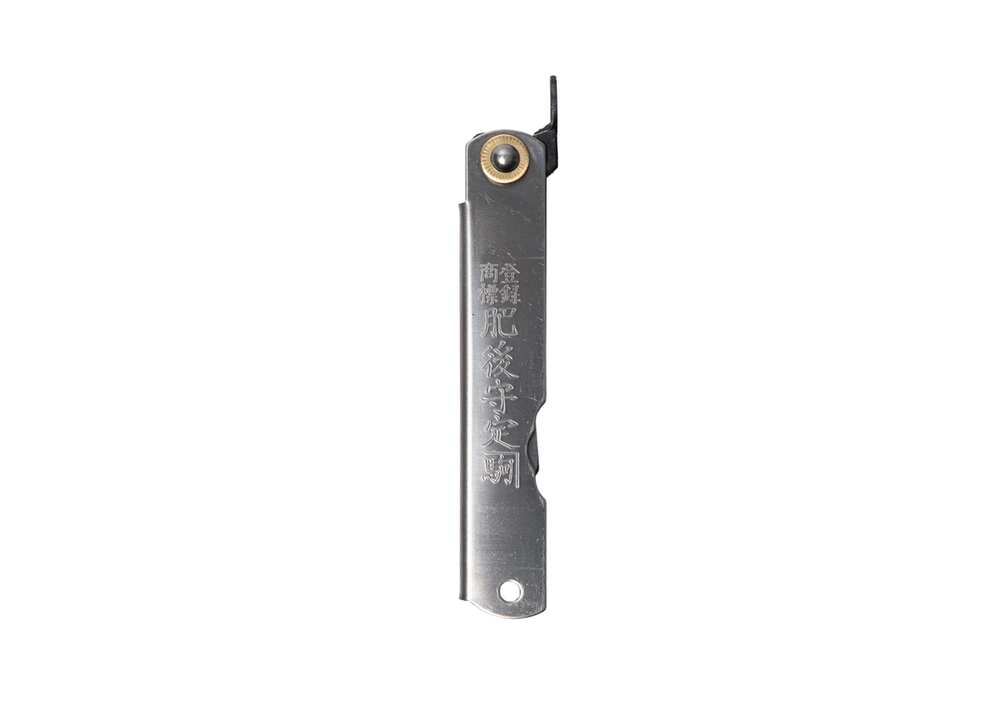 The Higonokami Blue Paper Steel Titanium L folding knife in its closed position, showcasing the sleek titanium handle stamped with traditional Japanese Kanji engraving and a classic brass pivot.