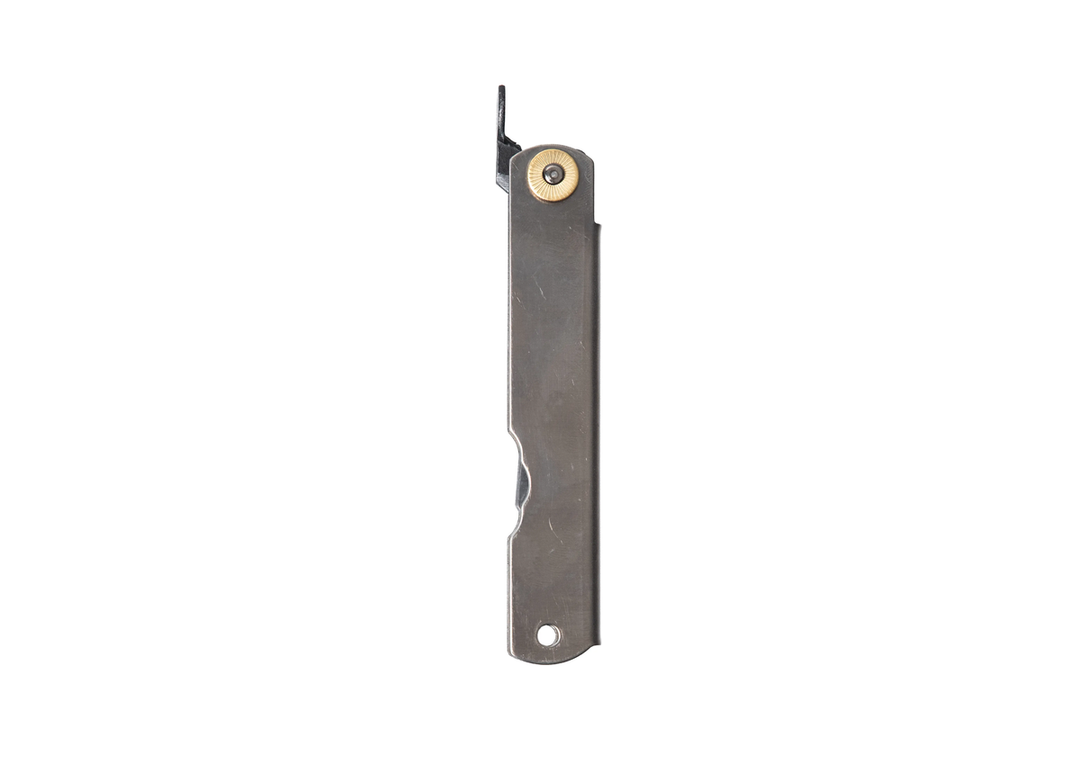 The reverse side of the closed Higonokami Titanium L friction folder, highlighting the smooth, minimalist titanium handle and the iconic chikiri lever protruding from the top.