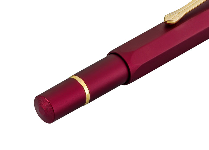 Close-up of the barrel end on the closed Kaweco Piston Sport AL Fountain Pen in Bordeaux, showing the smooth anodised red blind cap and gold trim ring.