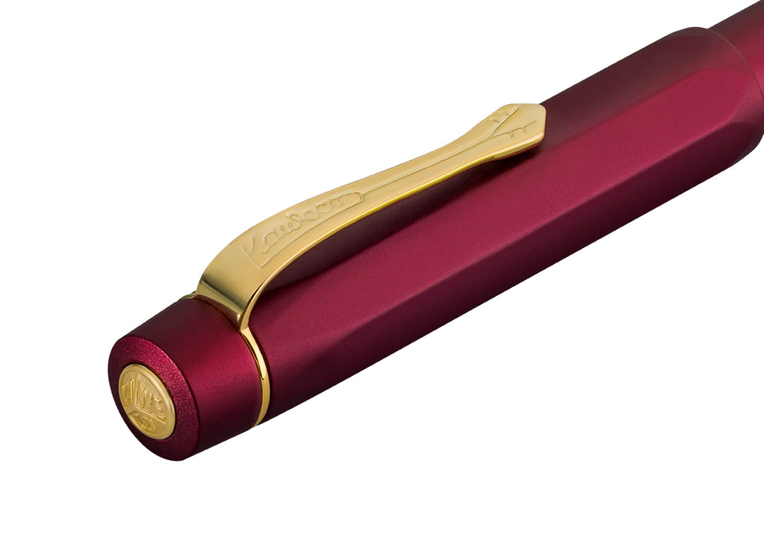 Close-up of the gold Kaweco logo finial and gold clip on the anodised red octagonal cap of the Kaweco Piston Sport AL Fountain Pen in Bordeaux.