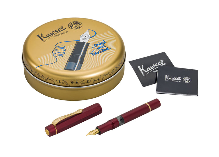 Kaweco Piston Sport AL Fountain Pen in Bordeaux shown open next to its anodised red cap, alongside the round gold Kaweco presentation tin and black informational leaflets.