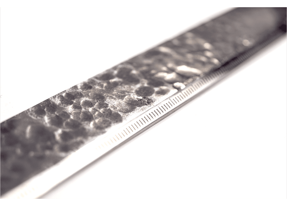 Macro close-up of the 3mm thick Kurogane Kazura metal ruler, showing the hammered texture and millimeter scale.