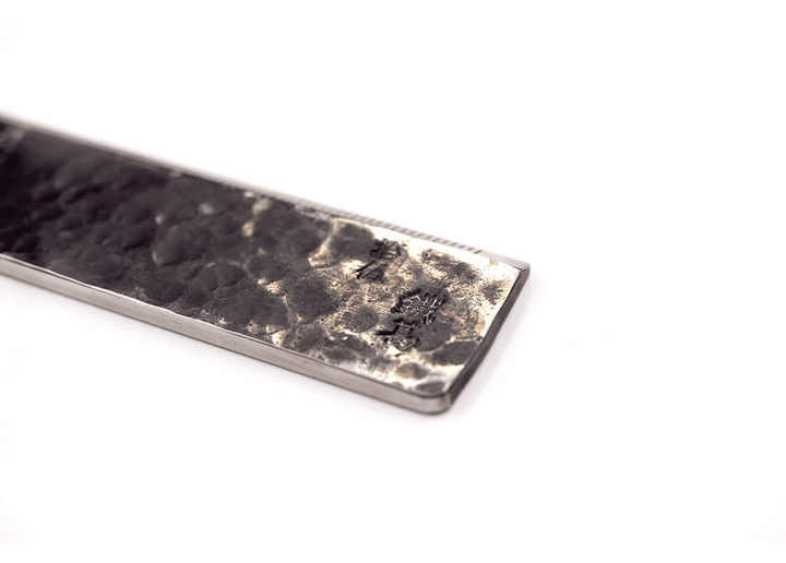 Detail of the textured end on a Japanese blacksmith-made straight ruler, highlighting stamped kanji numerals.