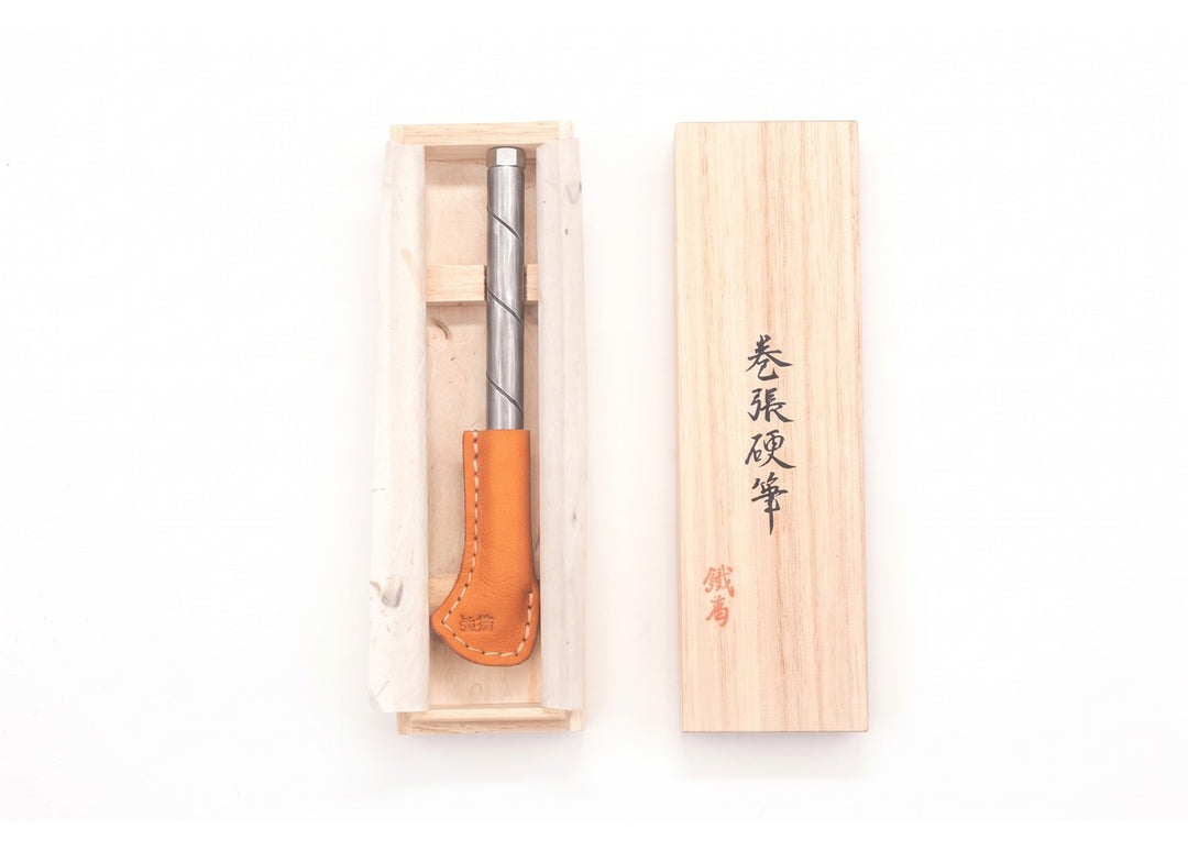 Open paulownia wooden box displaying a Kurogane Kazura forged steel pen for a traditional Japanese gift.