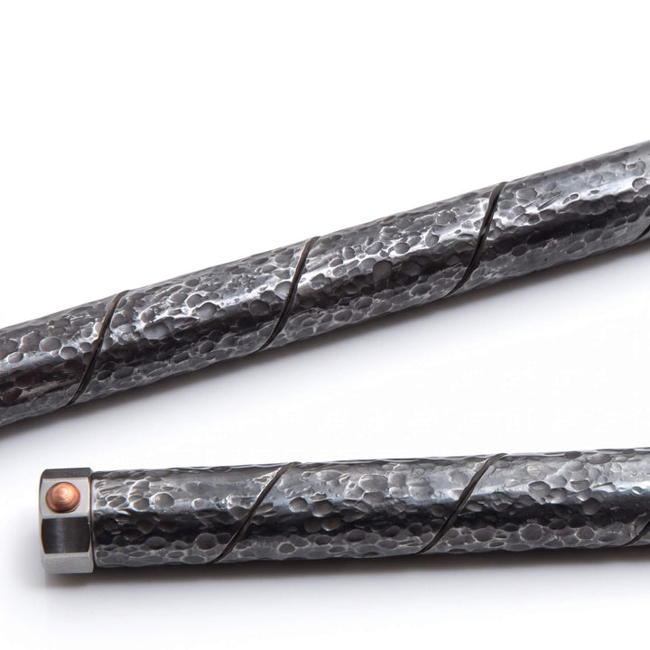 Macro shot of the Tsuchime hammered finish and spiral maki-hari seam on a dark steel pen barrel.