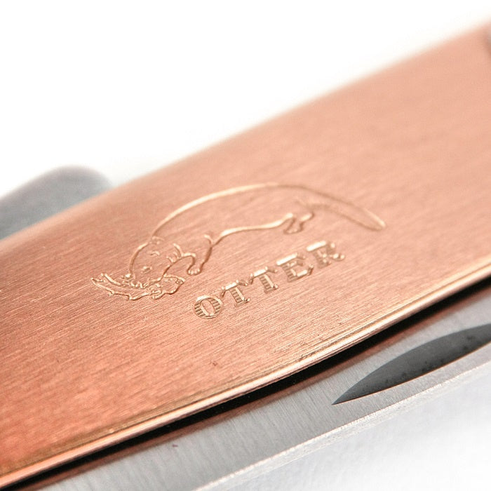 Extreme close-up of the traditional Otter Messer logo deeply stamped into the solid copper handle of the Mercator knife.