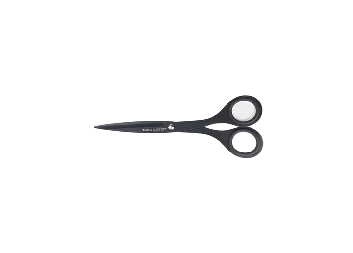 TOOLS to LIVEBY 6.5-inch matte black scissors closed and resting horizontally on a minimalist white background, showcasing the compact Japanese stainless steel profile and anti-glue Teflon coating.