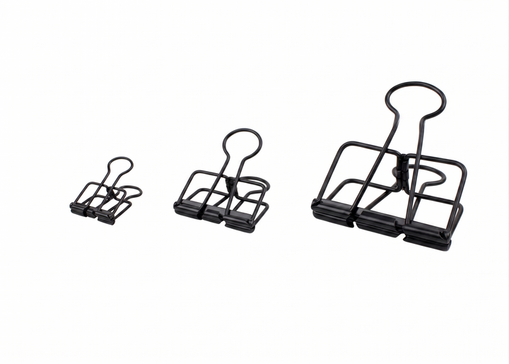 Three different sizes of TOOLS to LIVEBY matte black skeleton binder clips (small 19mm, medium 32mm, and large 51mm) are arranged horizontally on a plain white background, demonstrating the scale.