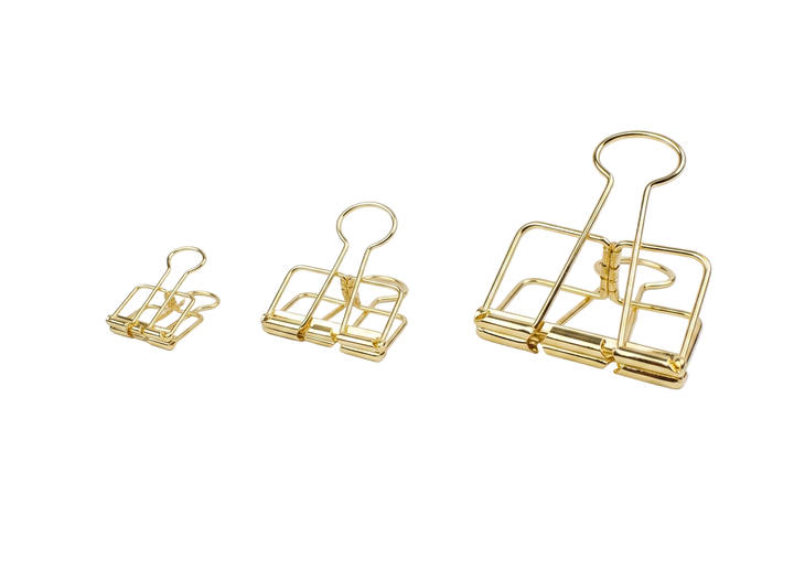Three sizes of TOOLS to LIVEBY radiant gold skeleton binder clips, including the small 19mm, medium 32mm, and large 51mm, arranged side-by-side against a crisp white background.