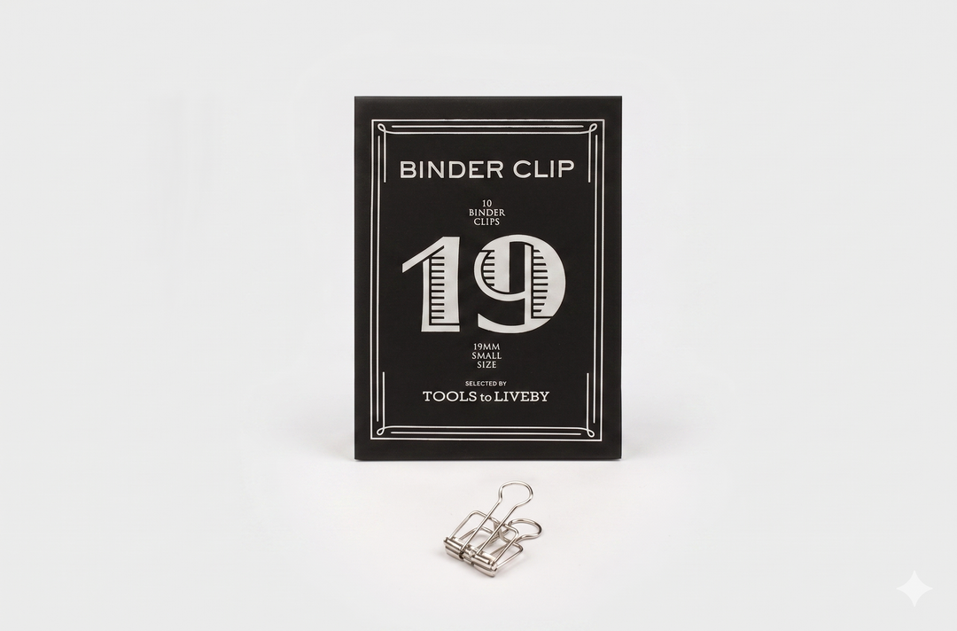 A small 19mm TOOLS to LIVEBY silver skeleton binder clip positioned neatly in front of its black product box, showcasing a distinct striped silver foil-stamped number 19.