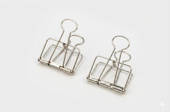 Two silver TOOLS to LIVEBY skeleton binder clips standing upright on their bases against a clean white background, showcasing the hollow see-through wire silhouette.