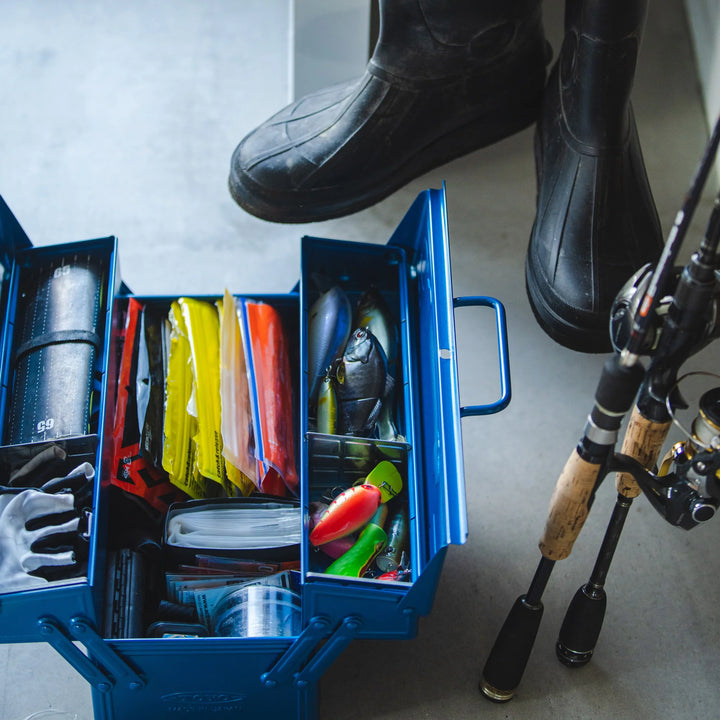 Open Blue TOYO ST-350 Cantilever Toolbox used as a heavy-duty fishing tackle box, storing lures and gear next to rubber boots and a fishing rod.