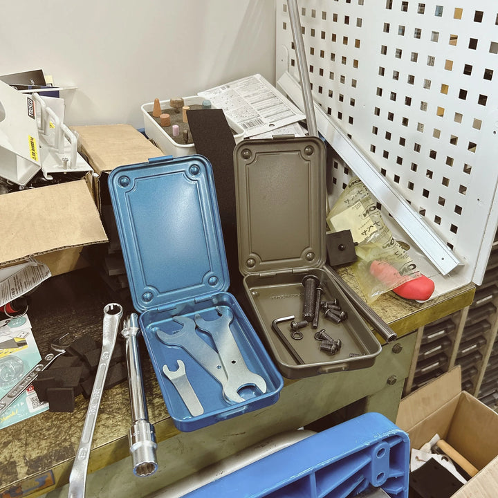 Open Blue and Moss Green TOYO T-152 Steel Toolboxes used on a workbench to organize flat hand tools, bolts, and hex keys.
