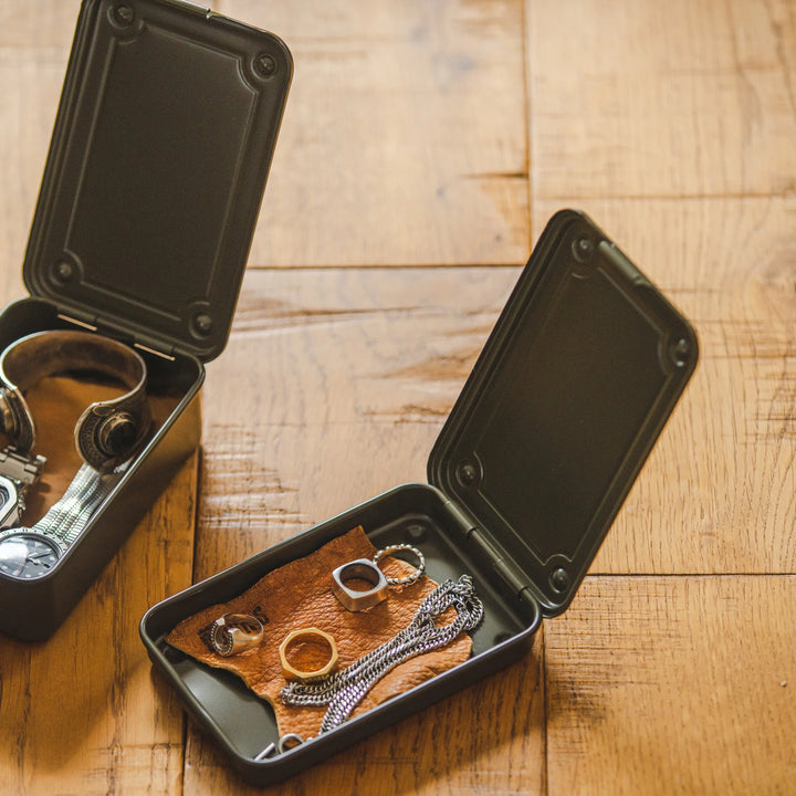 Open TOYO T-152 Steel Toolboxes used as flat EDC trays on a wooden desk, storing wristwatches, chains, and rings.