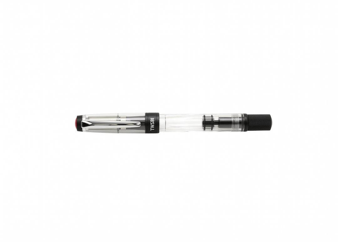 Perfectly horizontal profile of the capped TWSBI Diamond 580ALR Black fountain pen on a seamless white background, featuring the clear faceted barrel, matte black aluminum piston knob and cap band, and contrasting polished silver pocket clip.
