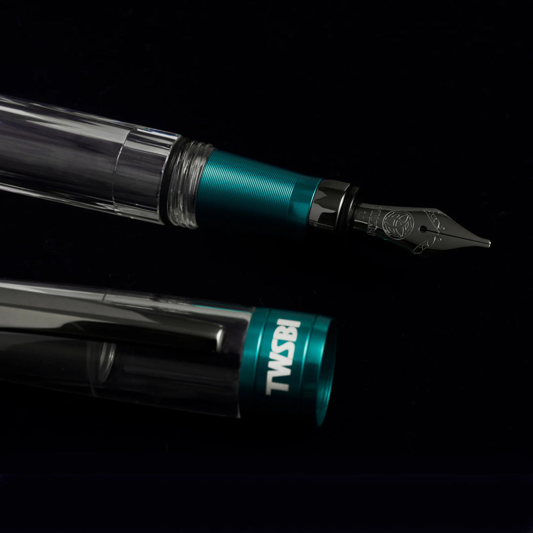 Macro close-up of the TWSBI Diamond 580ALR Caribbean Blue fountain pen, detailing the engraved black titanium stainless steel nib, textured matte blue grip section, and matching cap band.