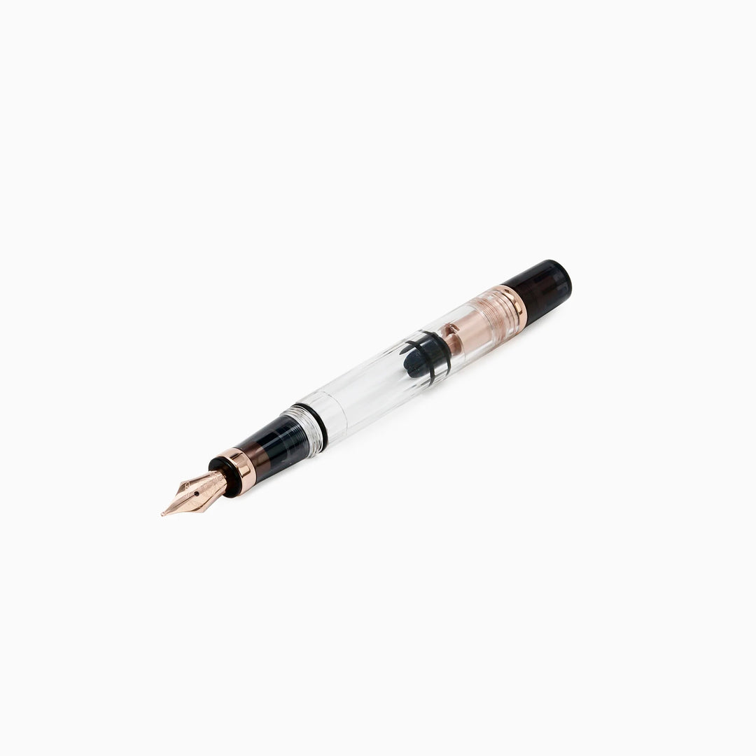 Angled view of the uncapped TWSBI Diamond 580 Smoke RoseGold II fountain pen, showcasing the rose gold nib, translucent smoke grip, and clear demonstrator barrel revealing the internal black piston seal.