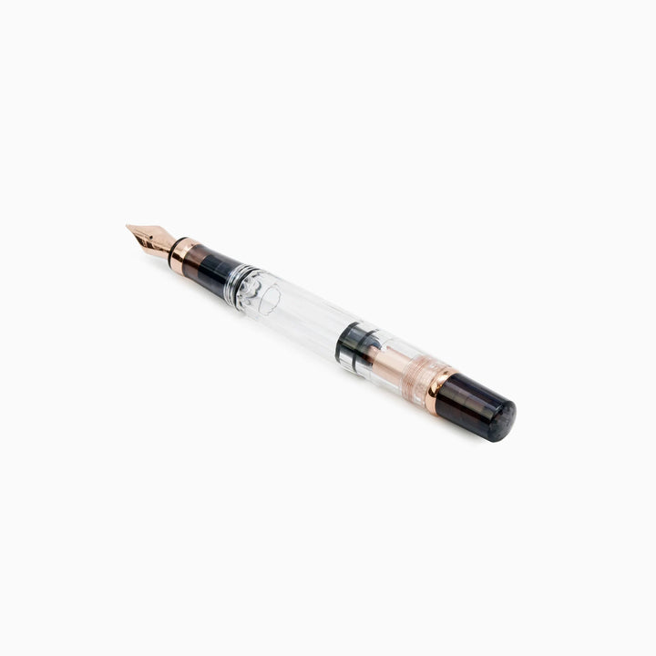 Detailed profile view of the TWSBI Diamond 580 Smoke RoseGold II fountain pen without its cap, emphasizing the crystal-clear resin barrel, high-capacity piston mechanism, and elegant rose gold turning knob accents.
