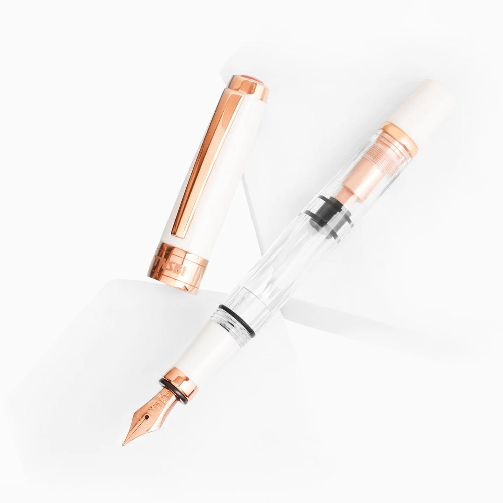 Artistic display of the TWSBI Diamond 580 White Rose Gold II fountain pen and cap resting on white geometric platforms, highlighting the striking contrast between the pristine white resin, clear faceted barrel, and premium rose gold trim.