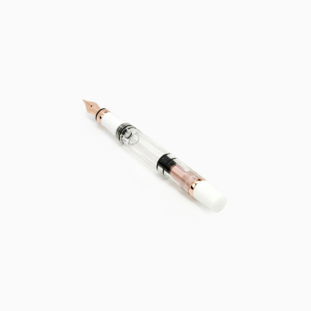 Angled view of the uncapped TWSBI Diamond 580 White Rose Gold II fountain pen, detailing the precision rose gold nib, crisp white grip section, and clear barrel revealing the internal black piston seal.