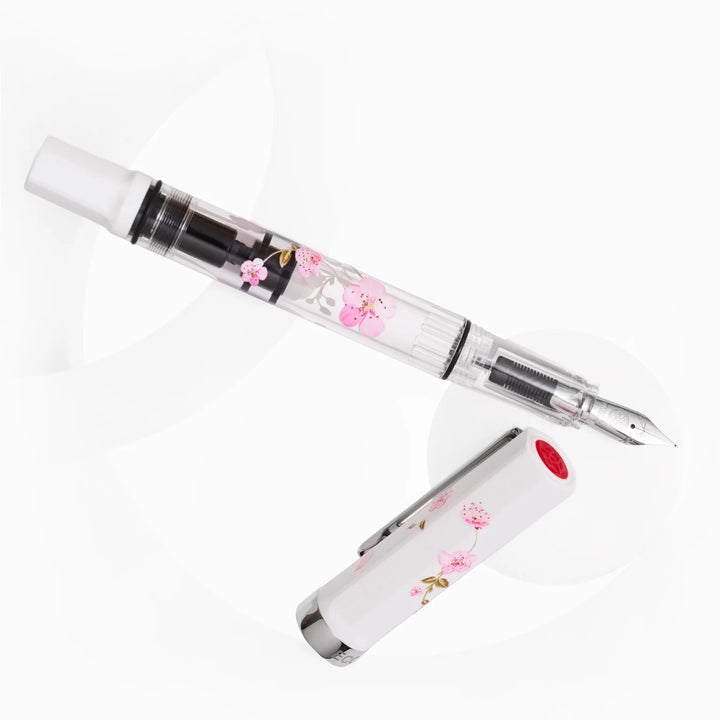 Uncapped TWSBI ECO Cherry Blossom fountain pen hovering above its cap, revealing the red TWSBI finial logo and clear demonstrator body.