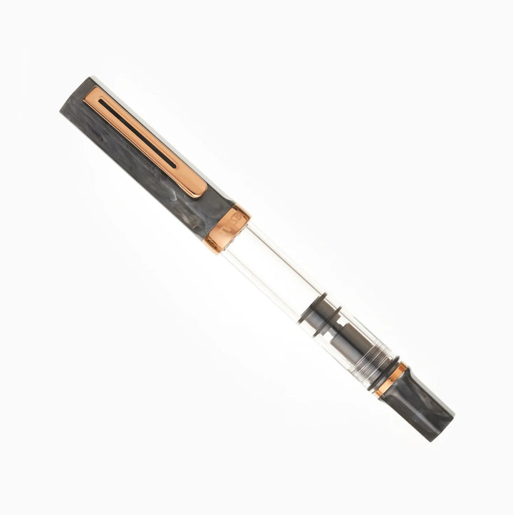 Angled product photograph of the fully capped TWSBI ECO Marble Bronze fountain pen on a pure white background. The image clearly displays the striking contrast between the swirled black marble resin cap and piston knob, the vintage bronze-plated trim, and the clear demonstrator barrel.