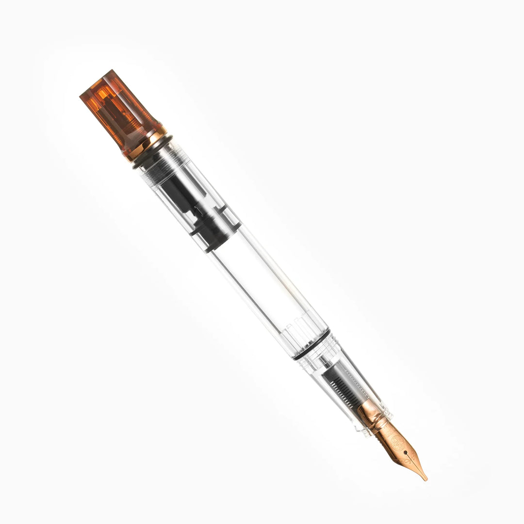 Uncapped, angled product photograph of the TWSBI ECO Rootbeer Bronze fountain pen resting on a seamless white background. The image clearly highlights the vintage bronze-plated stainless steel Jowo nib, the clear high-capacity demonstrator barrel, and the distinct translucent warm brown rootbeer resin piston knob.