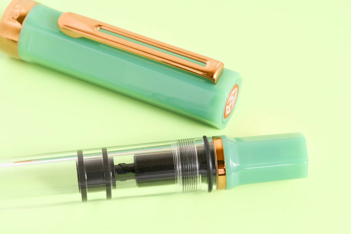 Detail view of the TWSBI ECO Jade Jelly Bronze transparent resin barrel, revealing the internal black piston-filling mechanism with the cap in the background.