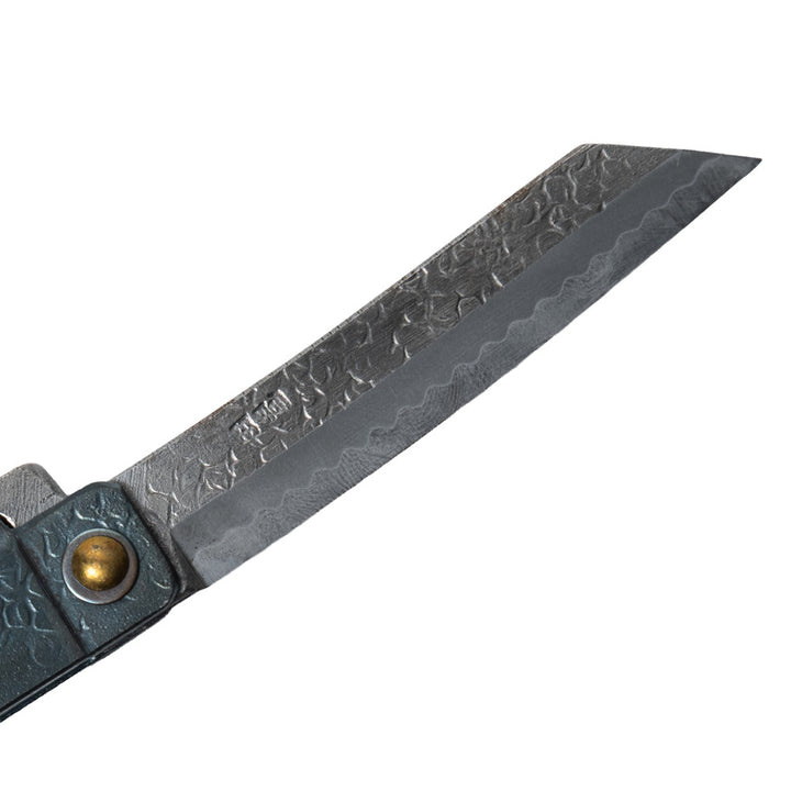 Macro close-up of the hand-forged Tomita blade, highlighting the traditional Higo profile, hammered spine, Japanese maker's mark, and characteristic Midareba wave pattern.