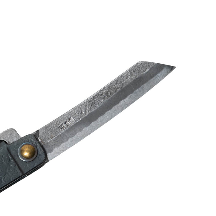 Macro close-up of the hand-forged Tomita blade, highlighting the traditional Higo profile, hammered spine, Japanese maker's mark, and characteristic Midareba wave pattern.