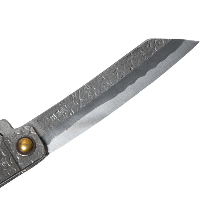 Macro close-up of the hand-forged Tomita blade, highlighting the traditional Higo profile, hammered spine, Japanese maker's mark, and characteristic Midareba wave pattern.