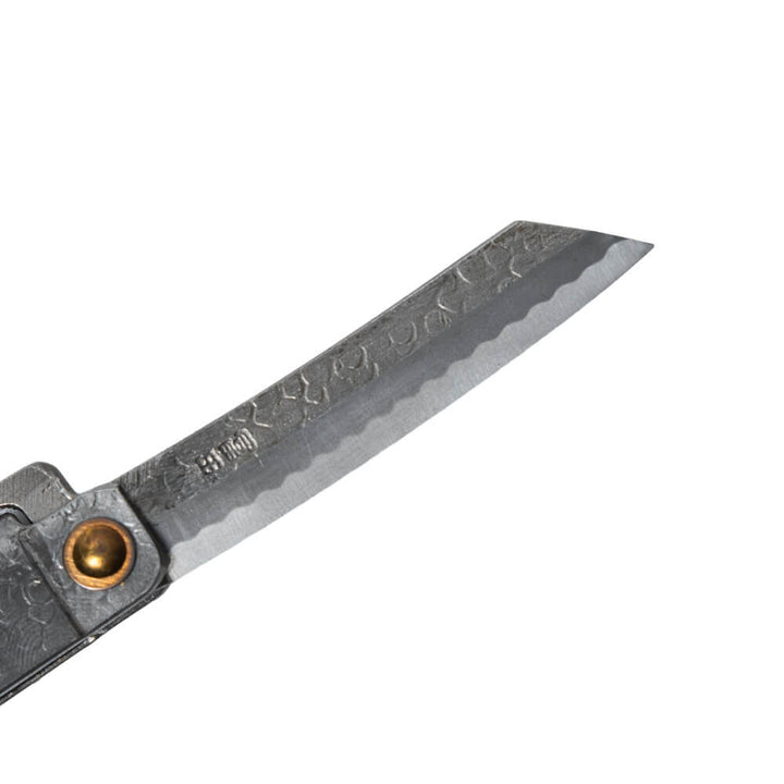 Macro close-up of the hand-forged Tomita blade, highlighting the traditional Higo profile, hammered spine, Japanese maker's mark, and characteristic Midareba wave pattern.