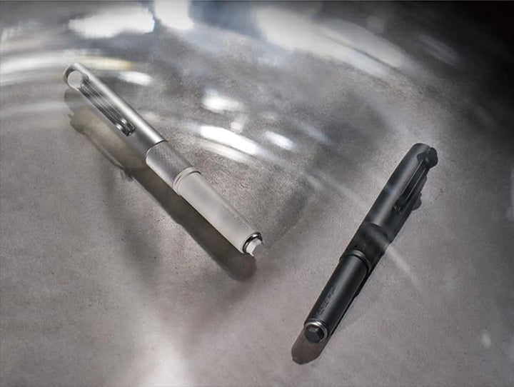 Uni-ball ZENTO Signature 3-Colour multi-pens in Silver and Black finishes displayed together on a reflective metallic background.