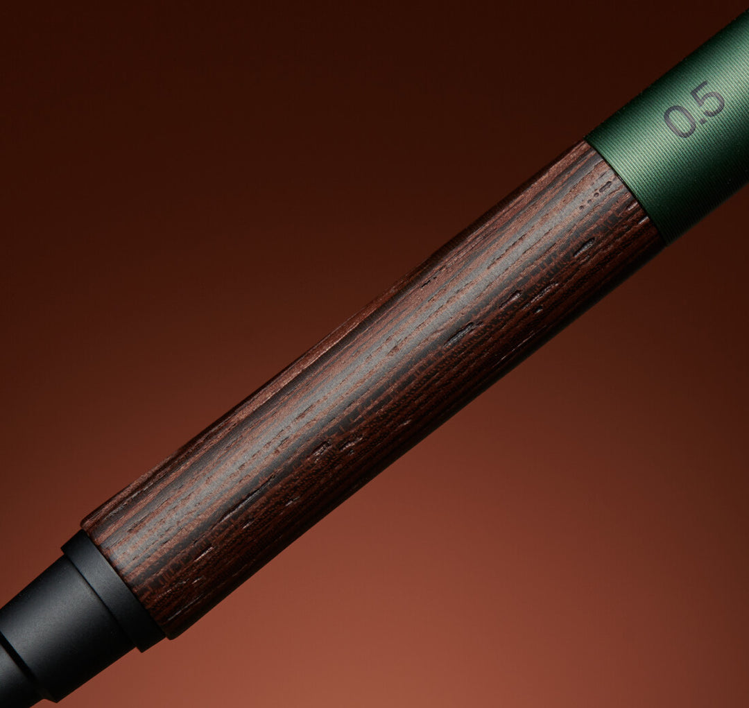 Macro view of the Uni Kuru Toga Wood mechanical pencil detailing the natural dark grain of the Wenge wood grip and the Forest Green aluminum body.