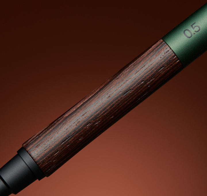 Macro view of the Uni Kuru Toga Wood mechanical pencil detailing the natural dark grain of the Wenge wood grip and the Forest Green aluminum body.