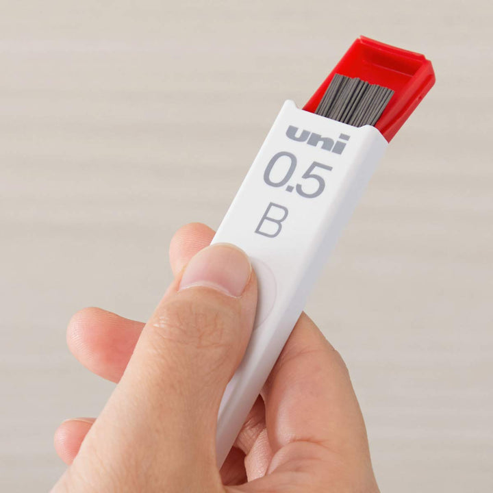 Hand dispensing uni 0.5mm B Smudge-Proof mechanical pencil lead from its minimalist slide case.