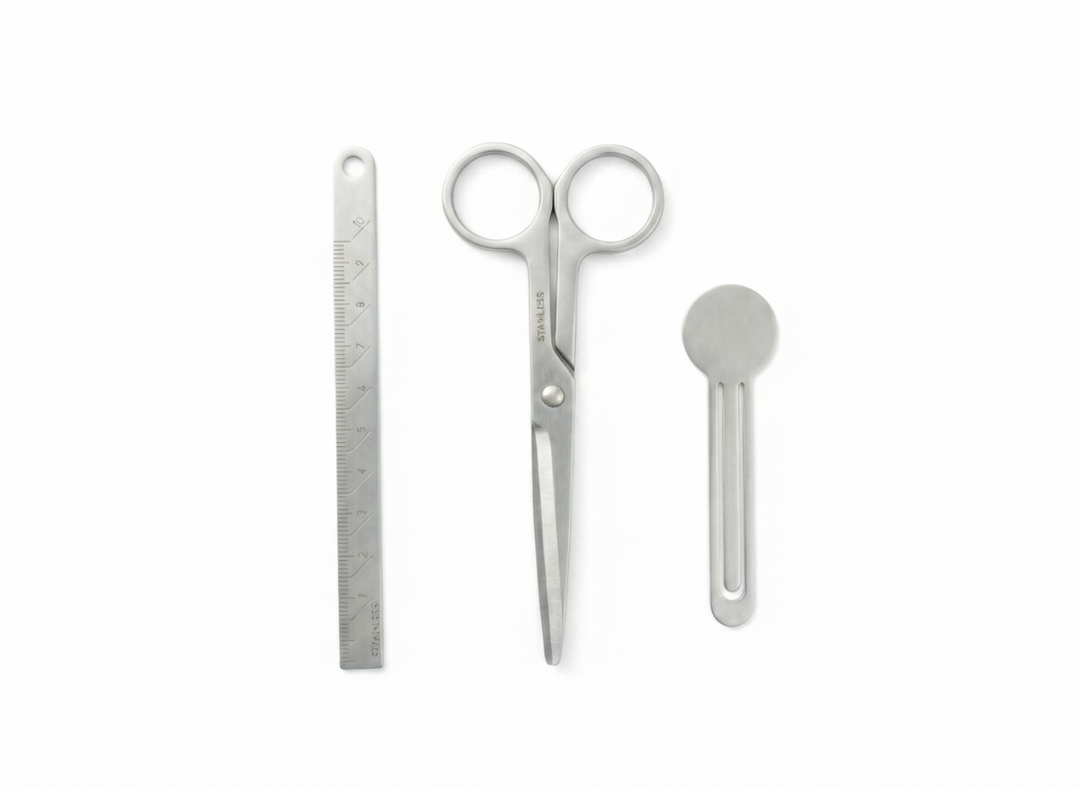 A flat lay product photo of the V-ROAD Ultra-Thin Recycled Stainless Steel Stationery Set arranged on a clean white background. The set features three minimalist tools with a matte brushed finish: a thin ruler on the left, scissors with round handles in the center, and a bookmark clip on the right.