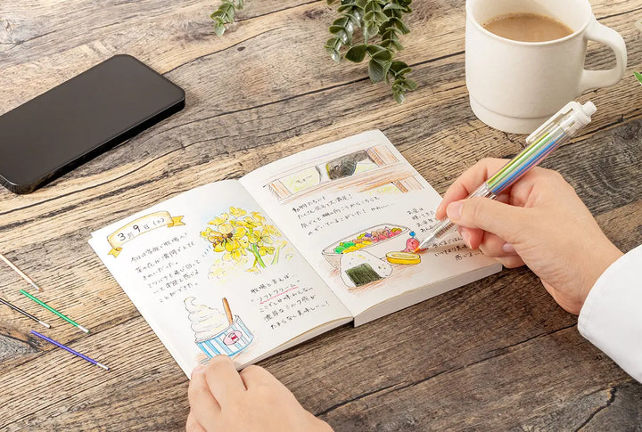 Person coloring in a book with Pentel Multi 8 Refill Leads (CH2 2.0mm) on a wooden table with a cup of coffee and phone.