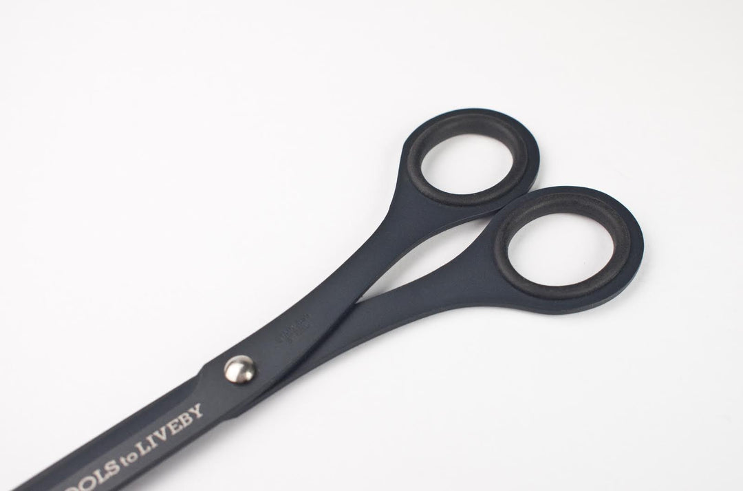 Macro detail of the TOOLS to LIVEBY 9-inch matte black scissors' handle, highlighting the ergonomic inner rubber grip rings, silver tension screw, and the tactical, ultra-matte Teflon finish.