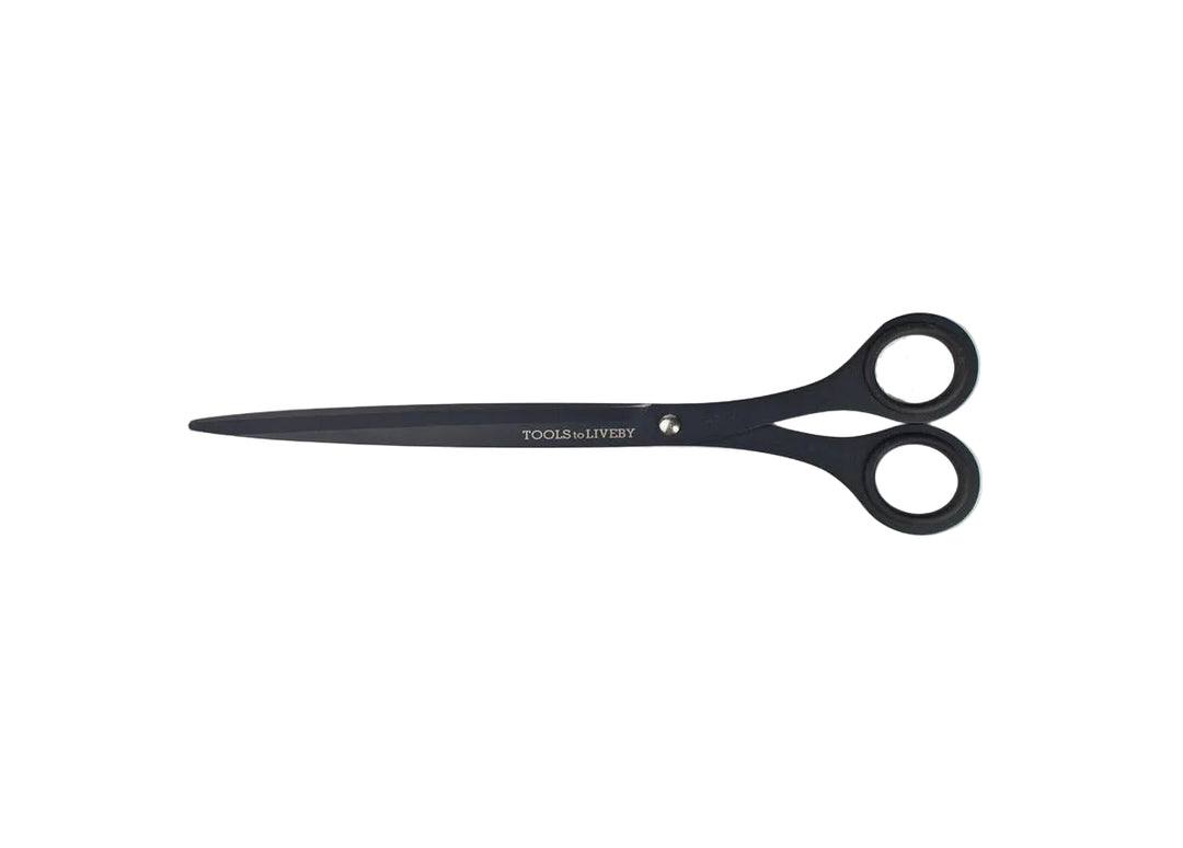TOOLS to LIVEBY 9-inch matte black scissors fully closed and resting horizontally on a minimalist white background, showcasing the elongated Japanese stainless steel profile and anti-glue Teflon coating.