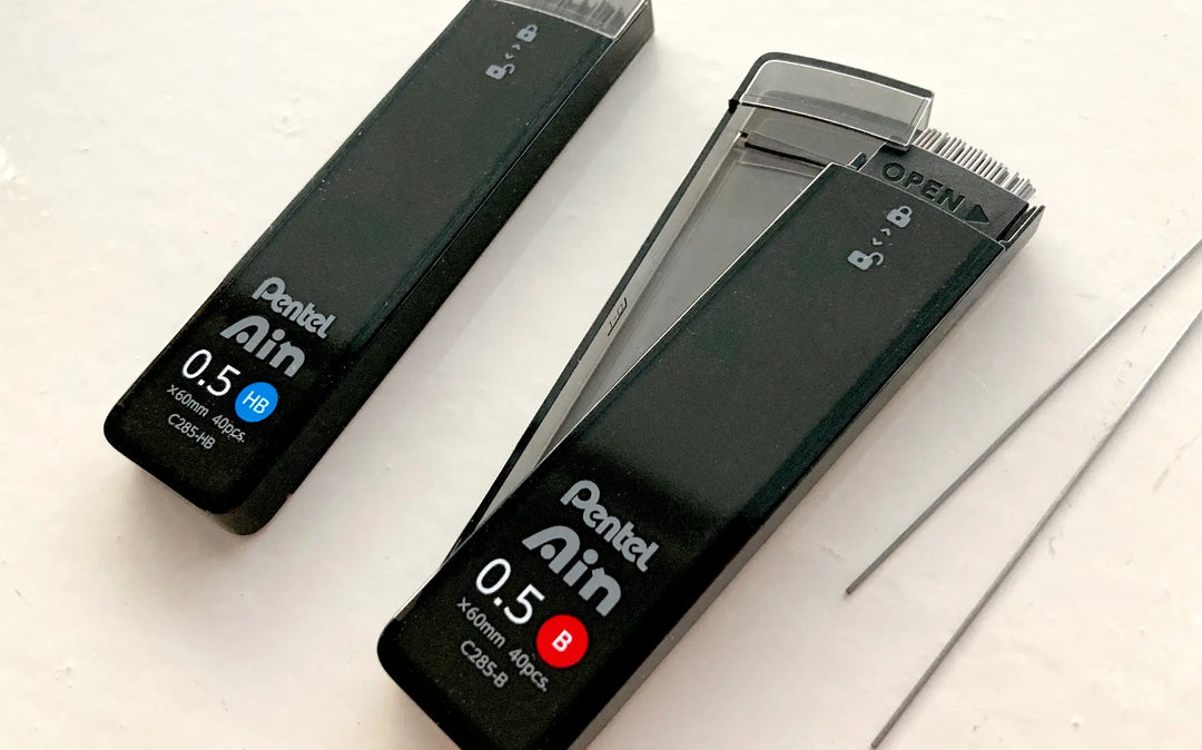 Close-up of Pentel Ain "Smart Slide" case mechanism. One-handed sliding lid design prevents spills and allows easy reloading of 0.5mm and 0.7mm leads.