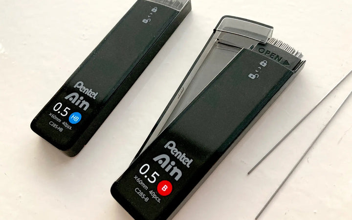 Close-up of Pentel Ain "Smart Slide" case mechanism. One-handed sliding lid design prevents spills and allows easy reloading of 0.5mm and 0.7mm leads.