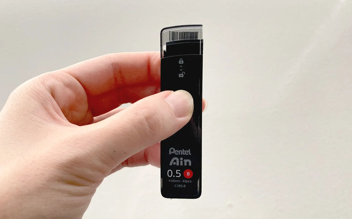 Close-up of Pentel Ain "Smart Slide" case mechanism. One-handed sliding lid design prevents spills and allows easy reloading of 0.5mm and 0.7mm leads.