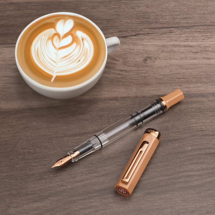 TWSBI ECO Fountain Pen – Caffe Bronze on a wooden surface with a cup of cappuccino.